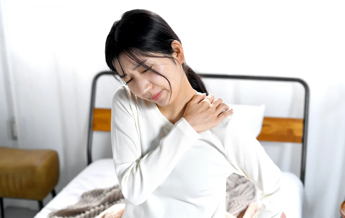 肩を押さえてつらそうな女性
